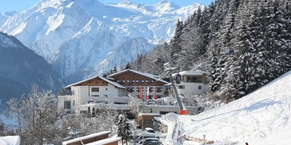 Hotels an der Piste - Skikurs direkt beim Hotel: eigene Skischule - Mittersill - Hotelansicht Winter - direkt an der Piste - amiamo - Familotel Zell am See