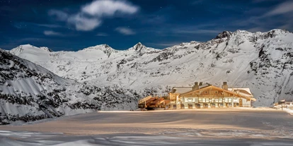 Hotels an der Piste - Après Ski im Skigebiet: Schirmbar - Hohe Mut Alm.
Hochgenuss am schönsten Bergrücken Tirols

Der Aussichtsberg Hohe Mut am südlichen Rand des Skigebiets serviert einen Rundumblick auf 21 Dreitausender und Gletscher. Doch damit nicht genug: Das 2.670 m hoch gelegene Bergrestaurant Hohe Mut Alm garniert die Aussicht mit kulinarischen Kreationen auf höchstem Niveau. Auf der großen Sonnenterrasse verschmelzen alle Sinneseindrücke zu einem einzigen Wort: Wow! Highlight jeden Mittwoch ab 18.30 Uhr ist der beschwingte Hüttenabend.

Glanzstück der Berggastronomie.
Neben der Bergstation der Hohe Mut Bahn II heißt die gemütliche Hohe Mut Alm hungrige Wintersportler willkommen. Viel Holz im traditionellen alpinen Stil erfüllt die Stuben mit warmer Gastlichkeit. Große Panorama-Fenster öffnen den Raum nach draußen, wo die Terrasse als chillige Lounge und sonniger Logenplatz zum Naturschauspiel dient. Passend zu diesem ganz und gar nicht alltäglichen Ambiente schmeckt auch die Kochkunst nach Mehr: Qualität, Hingabe und Raffinesse.

Jeden Mittwoch ab Mitte Dezember klingt der Skitag in Obergurgl-Hochgurgl am besten beim Hüttenabend in der Hohe Mut Alm aus. Auffahrt (kostenlos) ist um 18.30 Uhr – mit der topmodernen 8er-Kabinenbahn gelangt man komfortabel in 9 Minuten vom Ortszentrum Obergurgl zur Bergstation. Zum Empfang wärmt ein Punsch aus dem Kupferkessel, bevor das aufmerksame Service-Team ein Gourmetfondue mit Filets, Garnelen und vielen anderen Delikatessen auftischt. Livemusik krönt die Hüttengaudi in den Stuben, bevor es zurück ins Tal geht (Abfahrt ab 22.30 Uhr).

„Ja, ich will“: Immer mehr Paare sprechen die magischen drei Worte mitten im Obergurgler Winter aus. Die 2.670 m hoch gelegene Hohe Mut Alm hat sich als beliebte Hochzeitslocation etabliert und erfüllt alle Wünsche an den schönsten Tag des Lebens. So schwebt das Brautpaar in einer festlich geschmückten Hochzeitsgondel hinauf zur standesamtlichen Trauung am Berg, wo bis zu 230 Gäste auf der Sonnenterrasse und in exklusiven Stuben Platz finden. Auch um das Festmenü, Dekoration, Musik und Fotografen kümmern sich die Gastgeber gerne. Nur noch Ja sagen müssen Sie selbst. - Skigebiet Gurgl