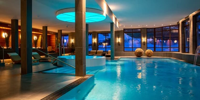 Hotels an der Piste - Pools: Innenpool - Götzens - Großes Schwimmbad im Wellnessbereich bei Abenddämmerung - Hotel Konradin****