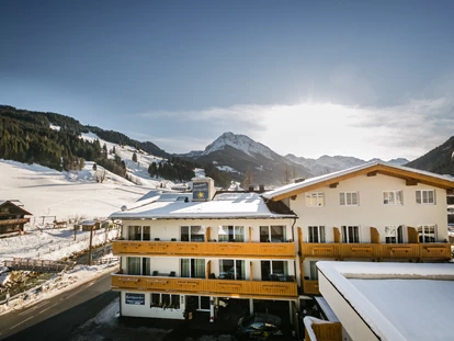 Hotels an der Piste - Hotel-Schwerpunkt: Skifahren & Tourengehen - Lammertal - Außenansicht im Winter mit Piste im Hintergrund - Familienhotel Botenwirt ***S
