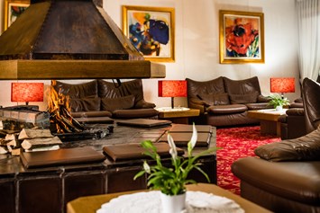 Skihotel: Sitzbereich mit offenem Kamin in der Hotellobby - Sporthotel Obereggen