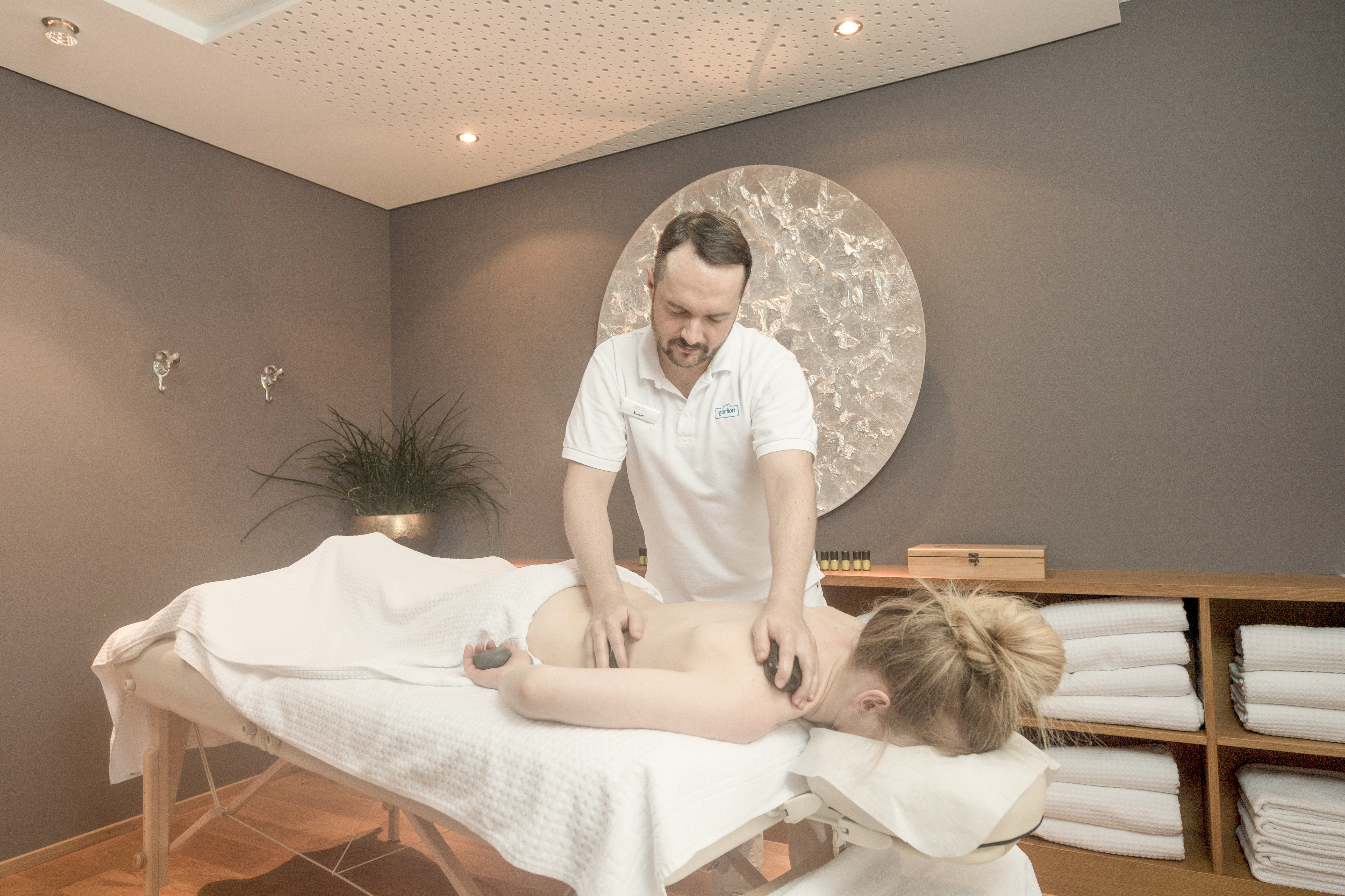 Skihotel: BergWellness 1600
Zwischen Kinderprogramm, Poolaction und Abendessen passt oft genau eine Sache gut hinein: eine Massage, eine Behandlung, ein Moment nur für euch. Genau dafür ist das BergWellness 1600 da. In unserem Spa in Liechtenstein geht es um Berührung, Pflege und bewusste Zeit zum Abschalten. Massagen lösen Verspannungen, Kosmetikbehandlungen schenken frische Impulse, wohltuende Rituale geben dem Urlaubstag eine neue Richtung. Sanfte Musik und feine Duftwelten begleiten jede Anwendung, damit ihr euch mause-wohl fühlt. Zur Pflege eurer Haut arbeiten wir mit nachhaltigen Produkten. Die machen nicht nur eine mause-weiche Haut, sondern sind auch gut zu unserer Natur. - Gorfion Familienhotel Liechtenstein - Wellness | Spa