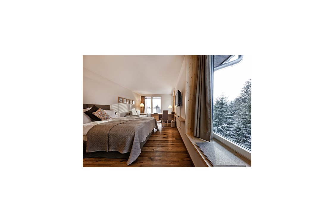 Skihotel: Doppelzimmer "Tgiasa da Lenn". Moderne Naturmaterialien, Erd-, Gras-, Holz- und Steinfarben im Innern verschmelzen mit der Gebirgswelt, die sich vor den grossen Fenstern auftut. Das alpine Design ist ehrlich und wertvoll zugleich – wie die Natur. - Valbella Resort