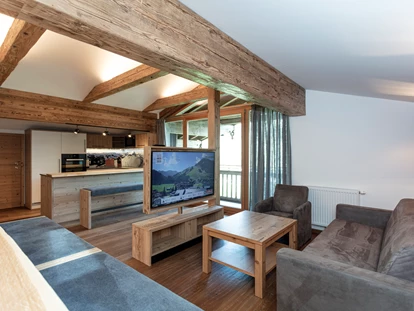 Hotels an der Piste - PLZ 6373 (Österreich) - Frisch renoviert: Der brandneue Aufenthaltsraum der "Galerie" mit großem Esstisch, Bar, drehbarem TV und luxuriöser Küche mit Natursteinplatte - Ferienwohnungen Perfeldhof