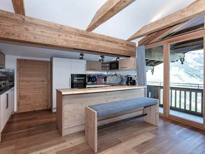 Hotels an der Piste - PLZ 6373 (Österreich) - Frisch renoviert: Der brandneue Aufenthaltsraum der "Galerie" mit großem Esstisch, Bar, drehbarem TV und luxuriöser Küche mit Natursteinplatte - Ferienwohnungen Perfeldhof