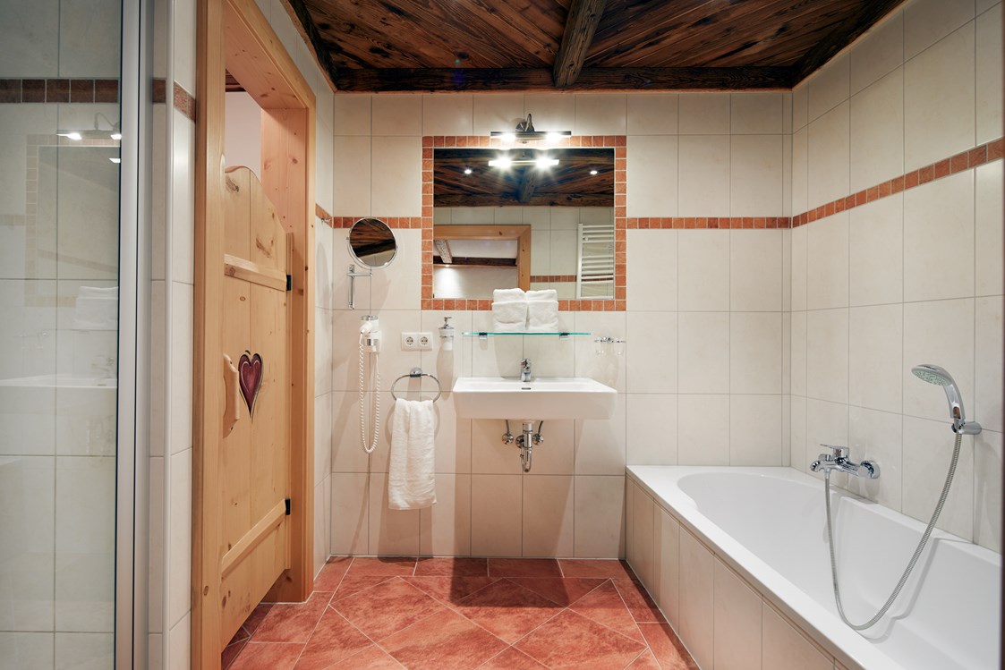 Skihotel: Badezimmer en suite mit Dusche, Badewanne, WC, Haarfön, Kosmetikspiegel - Almdorf Flachau
