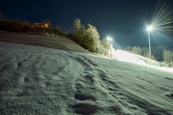 Skihotel: Aussicht von den Chalets auf die Skipiste mit Nachtskilauf - Chalets & Apartments Wachterhof