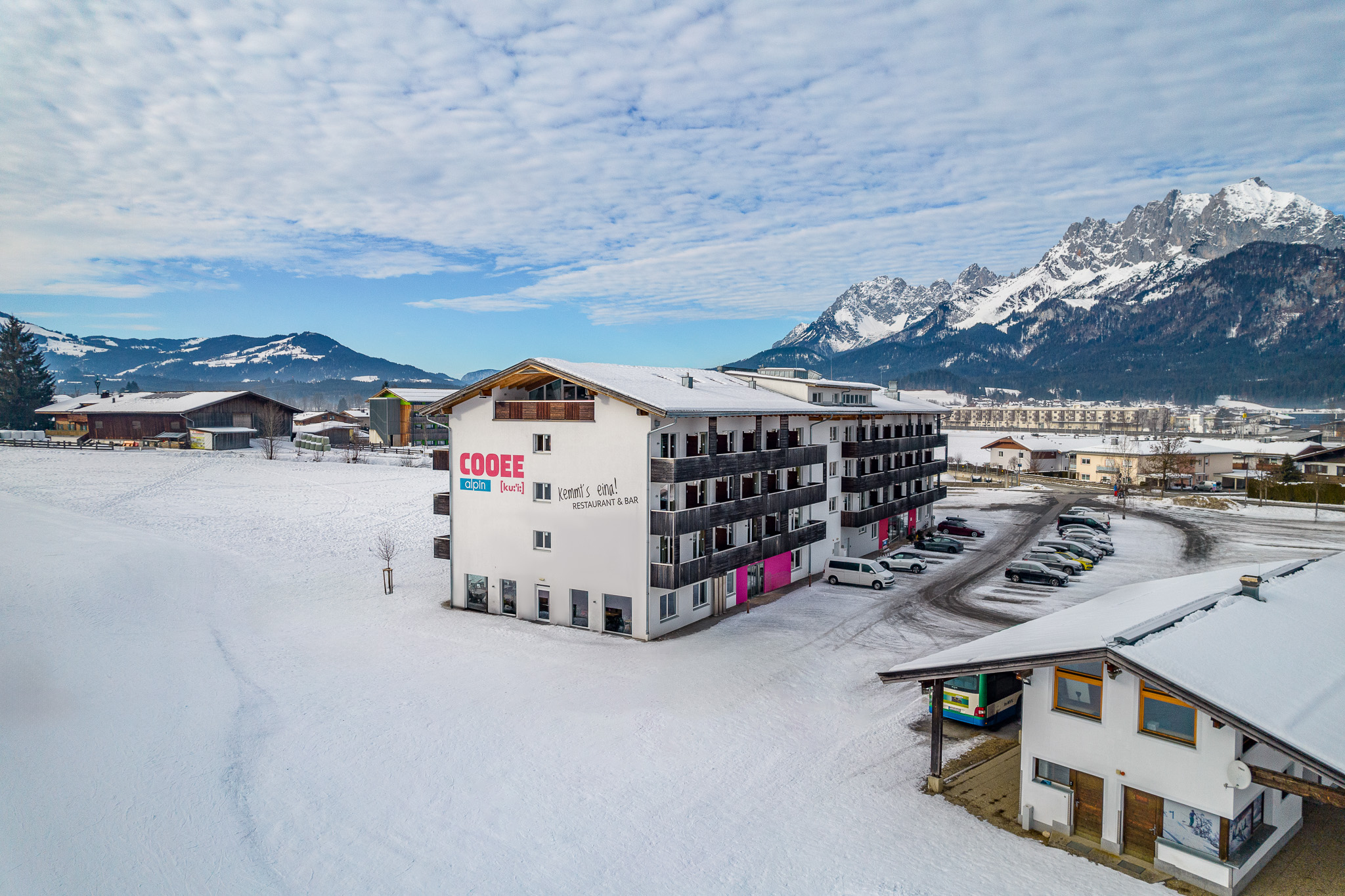 Skihotel: Außenaufnahme des COOEE alpin Hotels Kitzbüheler Alpen mit dem Wilden Kaiser im Hintergrund - COOEE alpin Hotel Kitzbüheler Alpen