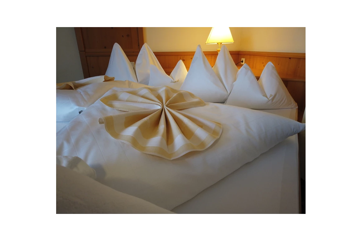 Skihotel: Das Bett in Ihrem Hotelzimmer in Obertauern ist mit hochwertiger Wäsche, die in der Inhouse Wäscherei gewaschen wird, ausgestattet. Die frische, saubere Bettdecke und die weichen Kissen laden Sie ein, sich nach einem aktiven Tag im Schnee hinzulegen und sich in die wohlige Wärme zu kuscheln. - Hotel Koch