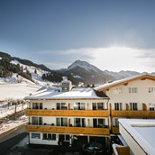 Hotels an der Piste: Außenansicht im Winter mit Piste im Hintergrund - Familienhotel Botenwirt ***S